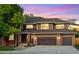 Charming two-story home featuring a two-car garage and a beautiful brick and wood facade against a colorful evening sky at 7873 Sweet Water Rd, Lone Tree, CO 80124