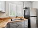 Well-lit kitchen featuring stainless steel fridge, wooden countertops and gray cabinets at 4592 Malaya St, Denver, CO 80249