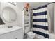 A neat bathroom features a sink with vanity, round mirror, and a shower with a navy-and-white striped curtain at 1216 S Uvalda St, Aurora, CO 80012