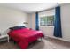 Sunlit bedroom showcases a bright window with blue curtains and cozy carpet, offering a peaceful retreat at 1216 S Uvalda St, Aurora, CO 80012