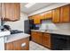 View of kitchen, boasting wooden cabinetry, black appliances, and grey countertops, creating a functional cooking space at 1216 S Uvalda St, Aurora, CO 80012