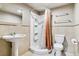 Bathroom with pedestal sink, white toilet, and stand up shower with orange shower curtain at 3762 S Fenton Way, Denver, CO 80235