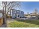 Backyard with a stone patio, furniture, grill, trampoline, grass area, and a gray two story house at 9990 Jasper St, Commerce City, CO 80022