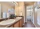 Bathroom with double sinks, framed mirror, and a door into the bath and shower space at 9990 Jasper St, Commerce City, CO 80022