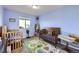 Bright bedroom with carpet, a window and two cribs with bedding and stuffed animal decorations at 9990 Jasper St, Commerce City, CO 80022