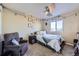 Cozy bedroom with a comfortable recliner, ceiling fan, window, string lights, and carpeted floors at 9990 Jasper St, Commerce City, CO 80022