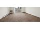 Bright, empty living room featuring neutral carpeting and an access door to the outside at 9300 E Center Ave # 2B, Denver, CO 80247