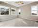 Sunlit bedroom features neutral walls, carpet, ceiling fan, and three windows showing outside views at 2601 Pemberly Ave, Highlands Ranch, CO 80126