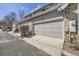 Attached two-car garage featuring brick accents, beige siding, and a concrete driveway at 4027 E Geddes Cir, Centennial, CO 80122