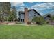 Beautiful blue house with a brick chimney, surrounded by lush greenery and mature trees in a well-maintained backyard at 7715 S Hudson Ct, Centennial, CO 80122