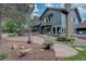 Attractive blue home with a brick chimney, expansive patio, and lush landscaping creating a serene outdoor living space at 7715 S Hudson Ct, Centennial, CO 80122