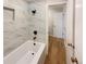 Updated bathroom with marble-look tile and a new bathtub at 1772 Robb St, Lakewood, CO 80215