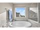 Bright bathroom with a luxurious soaking tub and large window with neighborhood views at 652 Pinecliff Dr, Erie, CO 80516