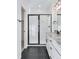 Modern bathroom featuring a glass-enclosed shower, granite countertops, black tile floor and black hardware at 3336 N Haleyville Ct, Aurora, CO 80019