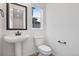 Bathroom featuring pedestal sink, toilet, medicine cabinet, black accents and hardwood floors at 3336 N Haleyville Ct, Aurora, CO 80019