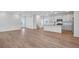 Open-concept living room with wood floors and a view of the kitchen with white cabinetry and stainless appliances at 3336 N Haleyville Ct, Aurora, CO 80019