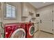 Functional laundry room featuring bright window, sink and modern red washer and dryer appliances at 11 Canon Pl, Greenwood Village, CO 80111