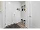 Bright entryway with white door, wood floors, and a built-in storage cubby with coat hooks at 6728 Mentha Dr, Castle Rock, CO 80108