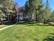 A spacious front yard with lush green grass and mature trees in a sunny, well-maintained neighborhood at 11576 E Bayaud Dr, Aurora, CO 80012