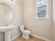 Cozy bathroom with a pedestal sink, tiled floor, toilet, and a window providing natural light at 17710 E Emilia Dr, Parker, CO 80134