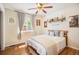 Well-lit bedroom with hardwood floors, a ceiling fan, and a decorative shelf above the bed at 1933 Chestnut St, Fort Lupton, CO 80621