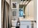 Small, clean bathroom with toilet, vanity, mirror, modern lighting, and shower at 7702 E 157Th Ave, Thornton, CO 80602