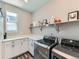 Well-organized laundry room with modern machines, white cabinets, and ample counter space at 7702 E 157Th Ave, Thornton, CO 80602