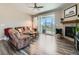 Bright living room featuring a sliding glass door, fireplace, ceiling fan, and hardwood floors at 7702 E 157Th Ave, Thornton, CO 80602