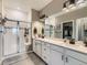 Bathroom featuring a glass-enclosed shower, double sinks, and ample storage space at 7702 E 157Th Ave, Thornton, CO 80602