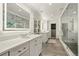 Bright bathroom featuring double vanity, glass shower, and large mirrors at 32 Glenmoor Dr, Englewood, CO 80113