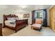 Comfortable bedroom with a rich wood bed frame, soft lighting, and a cozy sitting chair by the window at 32 Glenmoor Dr, Englewood, CO 80113