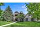 Charming two-story home with brick accents, balcony, lush green lawn, and mature trees at 32 Glenmoor Dr, Englewood, CO 80113