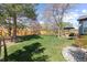 Picturesque backyard with a pristine lawn, mature trees, a wooden fence, and a cozy stone patio for outdoor entertaining at 7106 Cerney Cir, Castle Pines, CO 80108