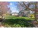 Lush backyard featuring a well-maintained lawn, mature trees, and a stone-enclosed patio seating area, ideal for outdoor enjoyment at 7106 Cerney Cir, Castle Pines, CO 80108