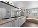 Bright bathroom featuring double sinks, a large mirror, and a separate tub at 7106 Cerney Cir, Castle Pines, CO 80108