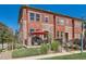 Charming townhome with a red brick facade, front porch, and manicured landscaping under a bright blue sky at 535 Elmhurst Way # A, Highlands Ranch, CO 80129