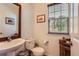 Well-lit powder room featuring a pedestal sink, toilet, and decorative accents, complemented by natural light at 535 Elmhurst Way # A, Highlands Ranch, CO 80129