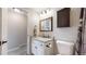 A bathroom features a white vanity with granite countertop, dark wood accents, and carpet on the floor at 32350 E 137Th Way, Brighton, CO 80603