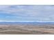 Expansive view showcases the scenic landscape with snow-capped mountains gracing the horizon under a blue sky with clouds at 32350 E 137Th Way, Brighton, CO 80603