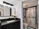 Bathroom features a black vanity, black framed mirror, and a shower with glass doors and marble walls at 2 Adams St # 1504, Denver, CO 80206