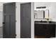 Bathroom with dark vanity, dark framed mirror, flowers, and a dark paneled door at 2 Adams St # 1504, Denver, CO 80206
