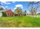 Expansive green lawn with a brick house, white fence, and mature trees at 10 Martin Ln, Cherry Hills Village, CO 80113