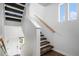 Bright staircase with carpeted steps, wood handrail, and a view to the entry door at 19096 E 55Th Ave, Denver, CO 80249