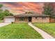 Charming brick home featuring a manicured lawn, walkway and an attached garage with a beautiful sky at 7995 Robin Ln, Denver, CO 80221