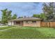 Charming brick home featuring a manicured lawn, walkway, attached garage, and privacy fence on a cloudy day at 7995 Robin Ln, Denver, CO 80221