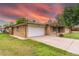 A charming brick home featuring an attached garage, expansive driveway with room for multiple cars and a colorful sky at 7995 Robin Ln, Denver, CO 80221