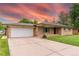 A charming brick home featuring an attached garage, expansive driveway with room for multiple cars and a beautiful sky at 7995 Robin Ln, Denver, CO 80221