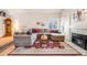 Inviting living room with a cozy fireplace, plush sectional sofa, and beautiful hardwood floors with a red rug at 5689 S Youngfield Way, Littleton, CO 80127