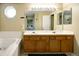 Bathroom featuring a double sink vanity, bathtub, and mirrors that expand the space at 4863 Quail Ct, Frederick, CO 80504