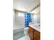 Bright bathroom with white tiled walls, a bathtub with shower, and a wooden vanity with sink at 4863 Quail Ct, Frederick, CO 80504
